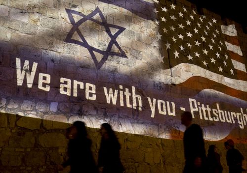 People walk past a projection on the Old City wall in Jerusalem in a commemoration of the victims of a deadly shooting at a Pittsburgh synagogue. A shooter opened fire at a Pittsburgh synagogue, killing 11 people in one of the deadliest attacks on Jews in US history. 