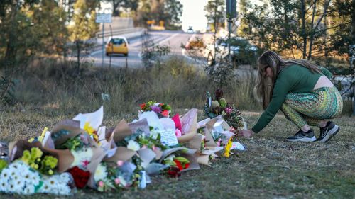 A woman lays flowers near the site of a bus crash on June 13, 2023 in Cessnock, Australia.