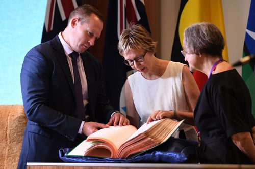 Queensland Minister for Digital Technology Mick de Brenni and Griffith University researchers Jennifer Menzies and Susan Horton look through the 1987 state cabinet papers. (Image: AAP)