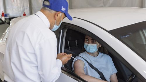 Dr Jamal Rifi administers a COVID-19 vaccine at a new drive-through vaccination clinic at Belmore Sports Ground in Sydney.