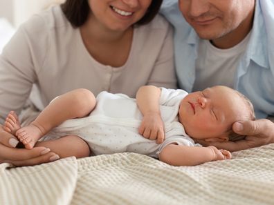 Mum and dad with their newborn baby on bed at home