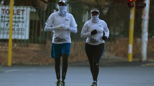 People jog wearing makeshift masks to protect against coronavirus, in Johannesburg, Friday, May 1, 2020.