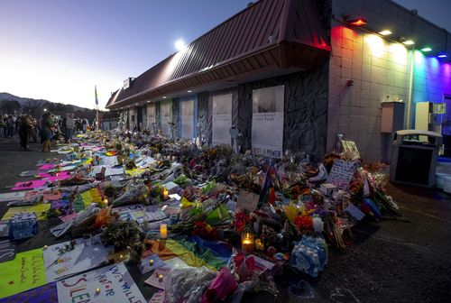 Mourners gather outside Club Q to visit a memorial, which has been moved from a sidewalk outside of police tape that was surrounding the club, on Friday, Nov. 25, 2022, in Colorado Spring, Colorado  