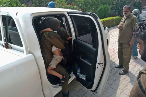 Police officers escort a relative and child of a couple who are wanted by British police in connection with the death of Sara Sharif, aged 10. 