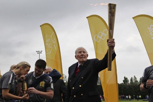 Sir Roger Bannister holds the Olympic Flame on the running track at Iffley Road Stadium in Oxford, England. (AAP)