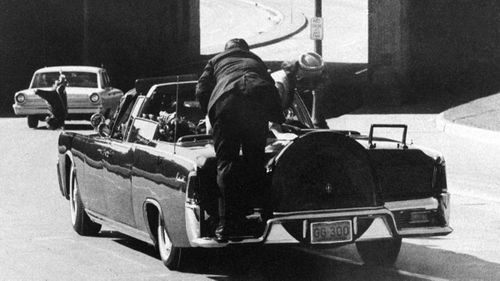 Secret Service Agent Clint Hill rides on the back of the presidential limousine after President John F. Kennedy was fatally shot in Dallas, Texas, on November 22, 1963. First lady Jacqueline Kennedy leans over the president.