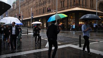 Pedestrians walk through the heavy rainfall in Sydney&#x27;s CBD.