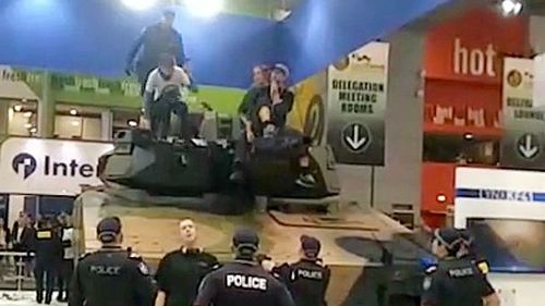 About a dozen anti-war protesters have forced their way into the Land Forces Weapons Expo at the Brisbane Convention Centre, with some chaining themselves to a tank. 
