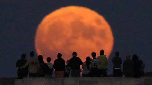 A rare Blue Supermoon rises over Lake Michigan as spectators watch from Chicago's 31st Street beach Wednesday, Aug. 30, 2023.