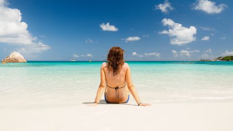 Backshot of a girl sitting on the shore of an idylic beach