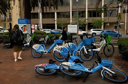 Pedestrians walk past e-bikes near the NSW State Library in Sydney.