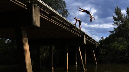 Local boys from Camden jump from the Macquarie Grove Road Bridge into the Nepean River as the temperature exceeded 45 degrees celsius in western Sydney pm February 11. (AAP)