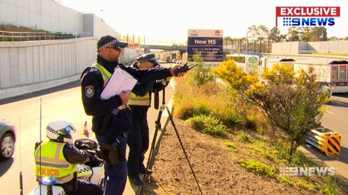 An officer with a digital stills camera using a high-powered zoom lens sets up where he can see city-bound peak hour traffic and photograph drivers doing the wrong thing. 