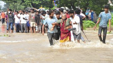 People wade through a flooded street in Nellore, in southern India. 