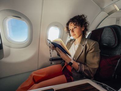 A focused Caucasian female relaxing while being on a plane.