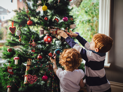 Two children putting ornaments on the Christmas tree