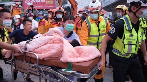 A trapped victim is carried on a stretcher as the victim was found and rescued by firefighters from a collapsed building in Yuli township, Hualien County, eastern Taiwan, Sunday, Sept. 18, 2022. A strong earthquake shook much of Taiwan on Sunday, toppling at least one building and trapping two people inside and knocking part of a passenger train off its tracks at a station.(Hualien City Government via AP)