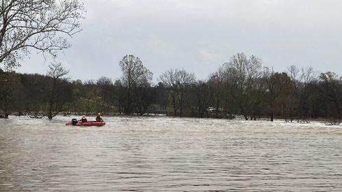 Patrol vehicles and lifeboats arrive from rescue efforts on the swollen river in Manes.