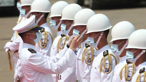 A Taiwan Navy honor guard captain adjusts team member's face mask during a launch ceremony for its first indigenous amphibious transport dock in Kaohsiung, southern Taiwan.