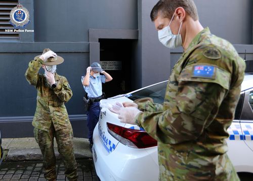 ADF and NSW Police officers put on protective clothing before conducting coronavirus isolation checks.