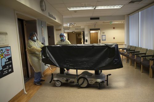 Two hospital staff enter an elevator with the body of a COVID-19 victim on a gurney at St. Jude Medical Center in Fullerton, California.