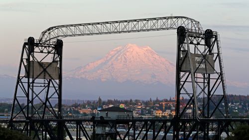 Mount Rainier is seen at dusk and framed by the Murray Morgan Bridge in downtown Tacoma, Washington. (Picture: AP)