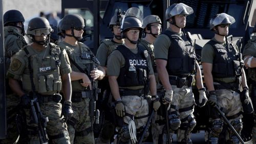 Police in riot gear watch protesters in Ferguson, Missouri, after a white police officer fatally shot Michael Brown, an unarmed black teenager, in the St. Louis suburb. (AP Photo/Jeff Roberson)