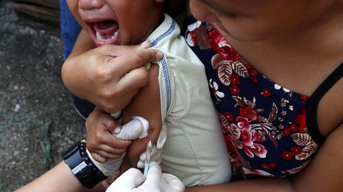 A Filipino boy reacts after receiving a measles vaccine during a nationwide response immunisation program at a street in Las Pinas city, south of Manila, Philippines
