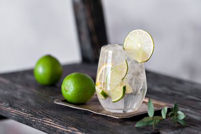 Cold cocktail with lime, lemon, tonic, vodka and ice on vintage background