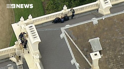 Police arrest a man on the roof of Government House.