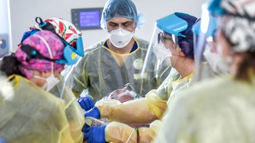 Une équipe de médecins et d'infirmières travaille sur un patient COVID-19 dans un service de soins intensifs de Melbourne.