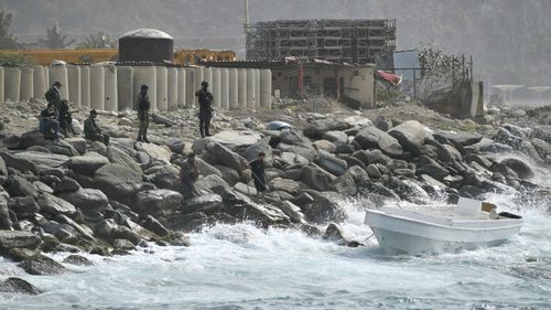 Security forces guard the shore area and a boat in which authorities claim a group of armed men landed in the port city of La Guaira, Venezuela