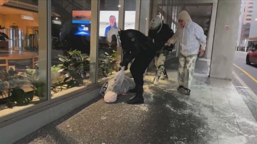 Protesters live streamed themselves spraying glass doors with paint on Flinders Street.