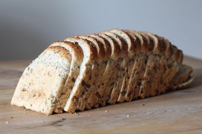 Loaf of seeded bread all sliced on the dining room table. Close details of the different seeds in the loaf. Healthy eating.