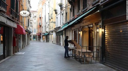 A waiter sets a table in a restaurant on an empty street in Venice, Italy. 