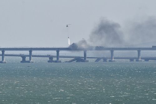 A helicopter drops water to stop fire on Crimean Bridge connecting Russian mainland and Crimean peninsula over the Kerch Strait, in Kerch, Crimea, Saturday, Oct. 8, 2022. 