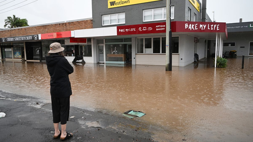 A woman looks at a flooded business today in Ballina. 
