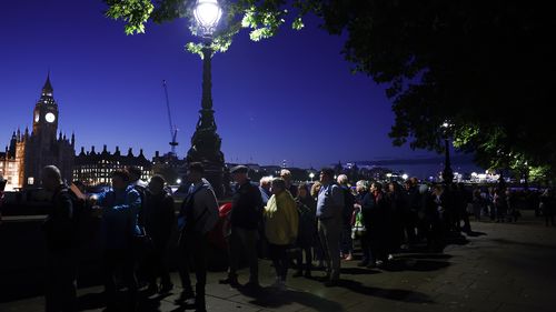 Members of the public stand in the queue in the evening for the Lying-in State of Queen Elizabeth II on September 16, 2022 in London, United Kingdom. Queen Elizabeth II is lying in state at Westminster Hall until the morning of her funeral to allow members of the public to pay their last respects. 