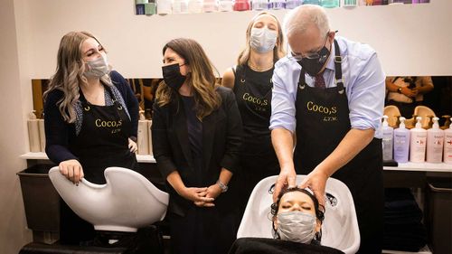 Scott Morrison washing a woman's hair during a visit to a salon in Mount Eliza.