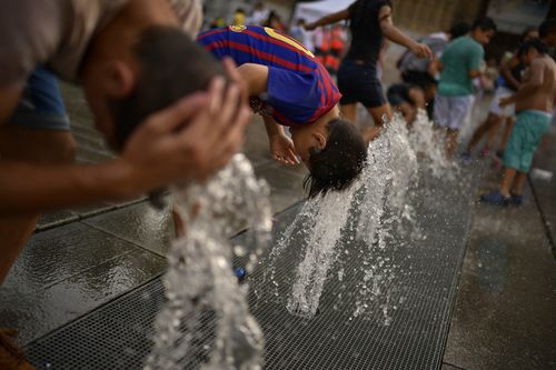 Those who couldn't get tot he beach were seen drenching themselves near fountains. Image: AAP