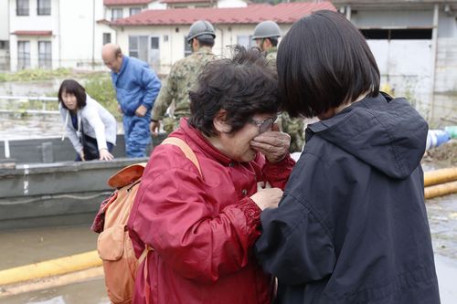 A woman, front left, cries in relief after being rescued from a flooded residential area following Typhoon Hagibis, in Marumori town, Miyagi prefecture, Japan Monday, Oct. 14, 2019.