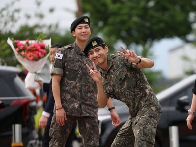 K-pop band BTS's members RM (L) and V (R) react after being discharged from a mandatory military service