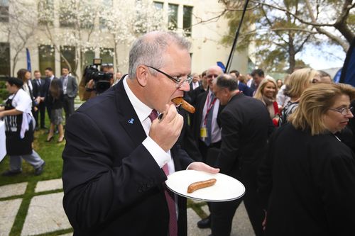 The PM tucks into a sausage during a Prostate Cancer Foundation barbecue event at Parliament House.
