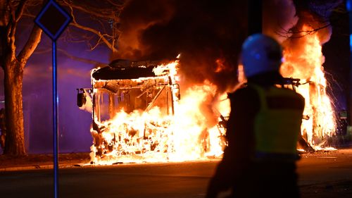 Riot police watch a city bus burn on a street in Malmo, Sweden.