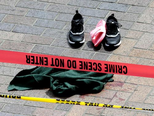 A green sweater, a pair of sneakers, a pink slipper and one black bike glove lay scattered on the sidewalk near a small splash of blood. Picture: AP