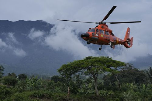 Membri ai Agenției Naționale de Căutare și Salvare (BASARNAS) zboară cu elicopterul pentru a livra materiale de ajutor într-un sat avariat de cutremurul de luni din Cianjur, Java de Vest, Indonezia, sâmbătă, 26 noiembrie 2022. 