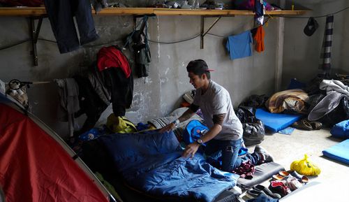 Kevin Roney Hernandez Melgar arranges his bedding in his sleeping area at the El Barretal migrant shelter in Tijuana. Melgar is among 12 men who share a living space at the shelter. 