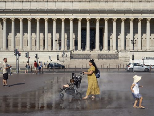 La gente cammina in una fontana durante un'ondata di caldo nel centro di Lione, nella Francia centrale, martedì 22 agosto 2023. 