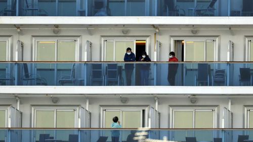 Passengers speak on balconies of the quarantined Diamond Princess cruise ship docked at a port in Yokohama, near Tokyo.