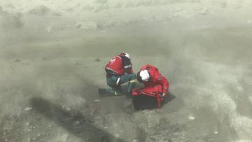 Two of the first responders kneeling among the moon-like dust of White Island following the deadly eruption.
